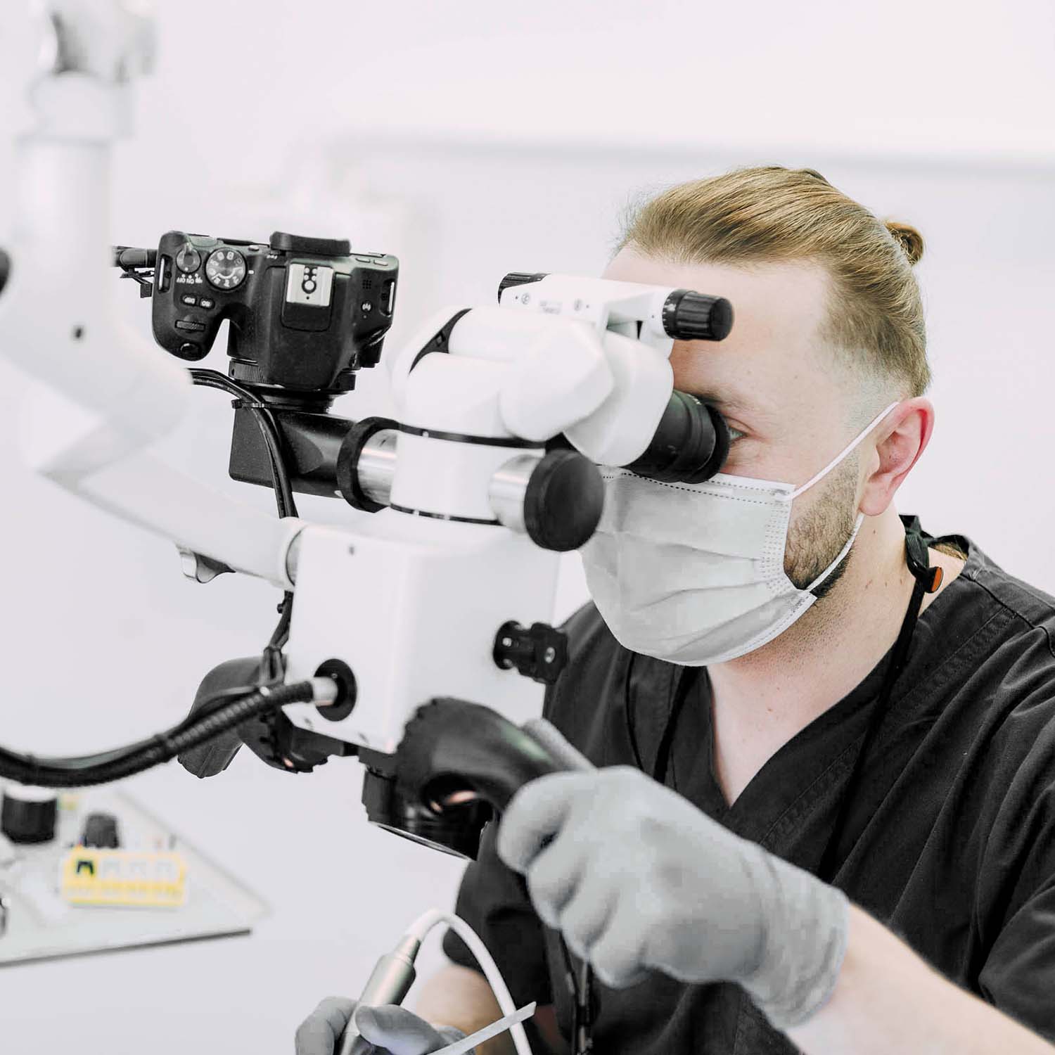 Ein Mitarbeiter der Zahnärzte am Lutherplatz schaut in ein Mikroskop bei den Zahnärzten am Lutherplatz in Langen.