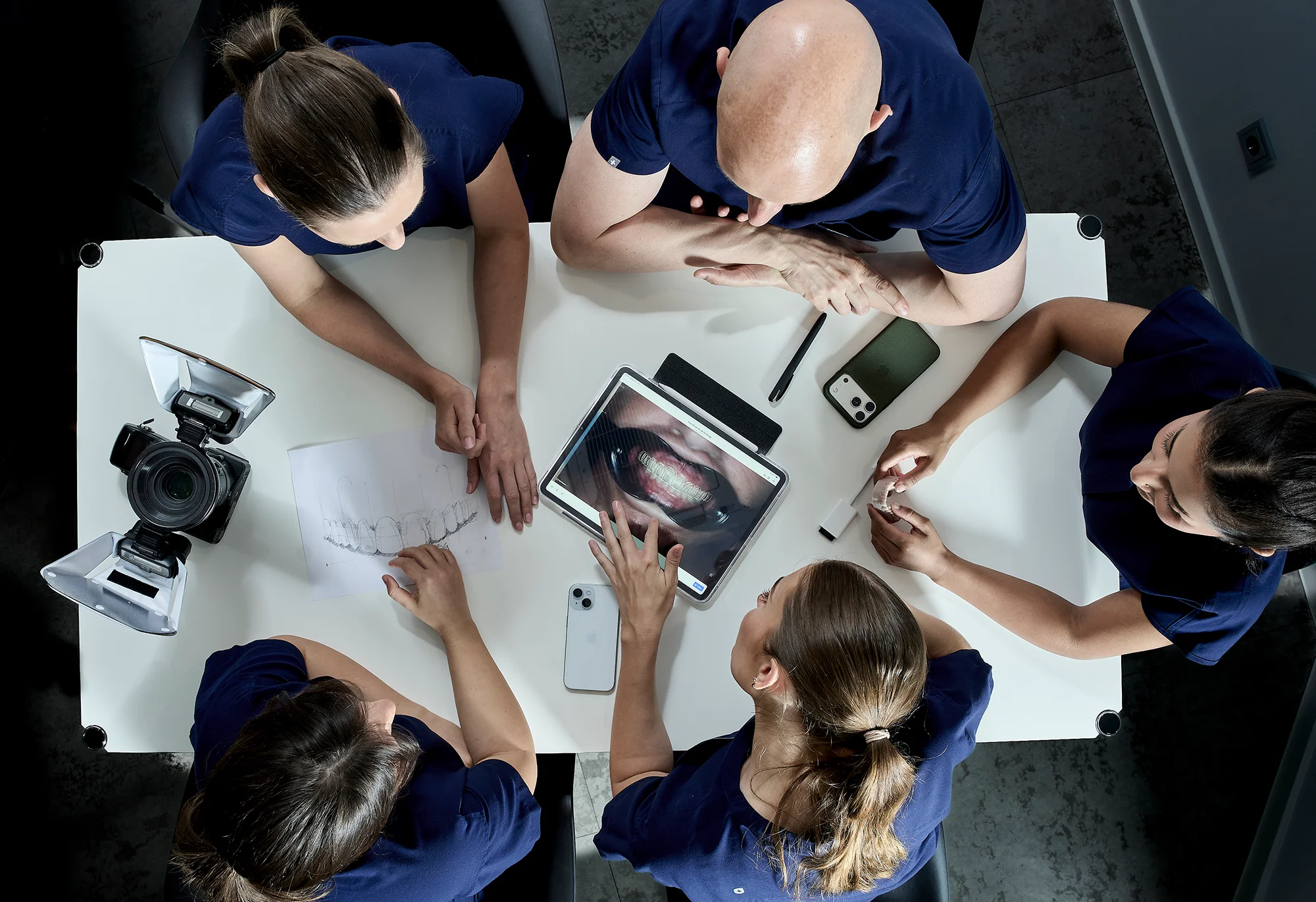 Zahnarztteam arbeitet gemeinsam am Tablet mit Röntgenbild, konzentrierte Zusammenarbeit in der Praxis am Lutherplatz